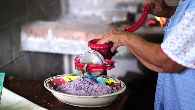 Mexican woman grinding purple corn to make tortillas. Traditional mexican food