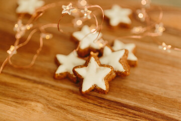 Gingerbread cookies in the shape of stars on a wooden brown natural table against a background of bokeh of New Year's golden lights. Christmas background. Winter card. Delicious pastries close-up
