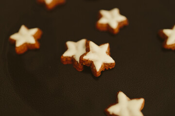 Gingerbread cookies in the shape of stars on a black table against a background of bokeh of New Year's golden lights. Christmas background. Winter card. Delicious pastries close-up
