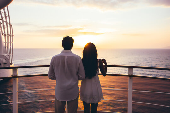 A young couple watching the sunset on the sea from a cruise ship deck