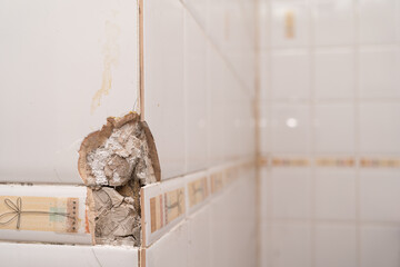 Close up of a cracked ceramic tiles surface. Cracked, broken bathroom wall tiles or panels.