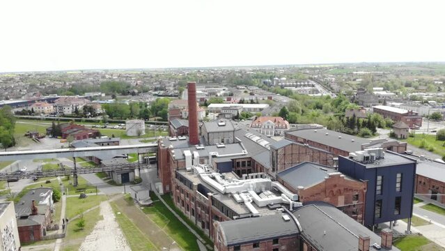 Aerial orbit tilt-up shot of the Arche Hotel Żnin inside old sugar factory in Poland. The tall chimney of the factory is a famous landmark, rising above the surrounding landscape