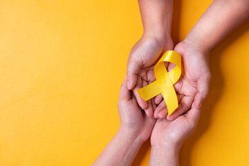 yellow ribbon on the hand of a cancer sick person, world cancer day, healthcare and medicine...