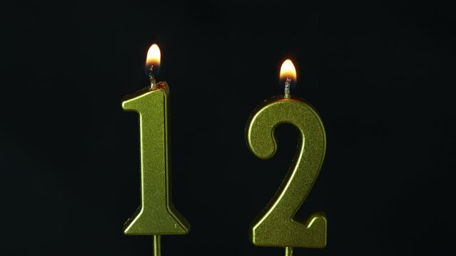 close up on the gold number twelve candle on a dark background.
