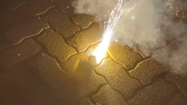 a firework cracker quickly spinning on the ground with spark and smoke during a diwali festival celebration at night