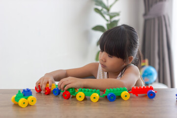 Cute funny preschooler little girl in a colorful shirt playing with construction toy blocks...