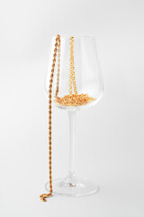 Wine glass and golden jewelry inside on white background