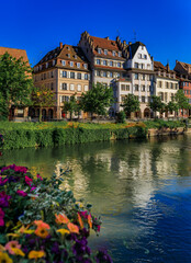 Fototapeta premium Ornate traditional half timbered houses with steep roofs above the Ill River with blooming flowers, the historic center of Strasbourg, Alsace, France