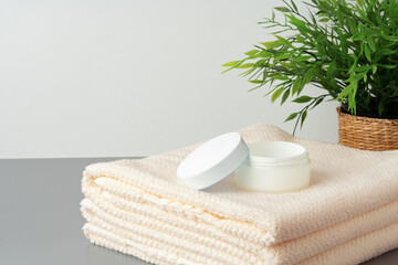 White cosmetics container mockup with towels on gray background