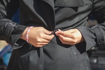 Woman fasten button a black clothes.