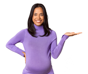 Young Filipina woman expecting a baby in studio showing a copy space on a palm and holding another hand on waist.