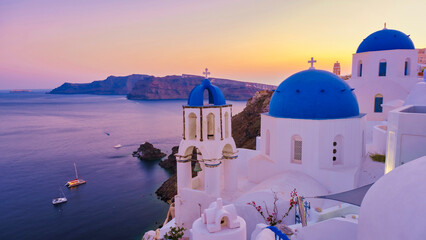 White churches an blue domes by the ocean of Oia Santorini Greece, traditional Greek village - obrazy, fototapety, plakaty