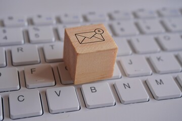 Wooden cube with new email notification icon on top of keyboard. Communication and technology concept