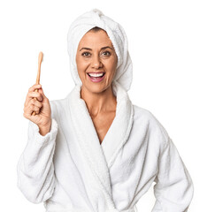Middle-aged woman with toothbrush in bathrobe in studio