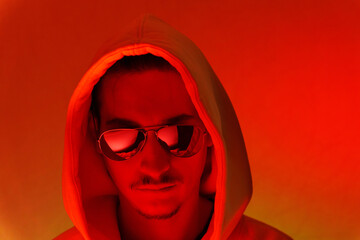 Red background light studio close-up portrait of a male model with a mustache and beard wearing sunglasses