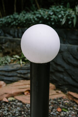 a round white garden lamp installed in the yard of a villa