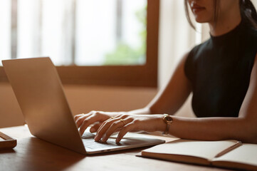 A beautiful Asian woman working on her laptop, typing on the keyboard, responding to emails.