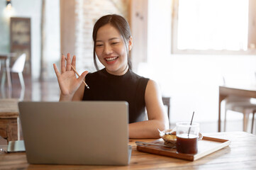 A woman is joining an online meeting with her team while working remotely at the coffee shop.