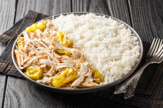 Slow Cooker Mississippi Chicken with ranch seasoning, dried au jus gravy mix and pepperoncini peppers served with rice closeup on the plate on the table. Horizontal