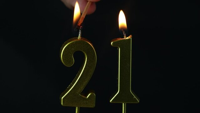 close up on the gold number twenty-first candle on a dark background.
