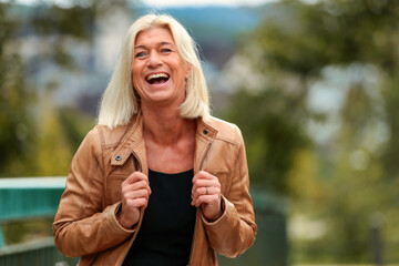 Woman around 50 years old in leather jacket, head portrait, laughing and looking into the camera..