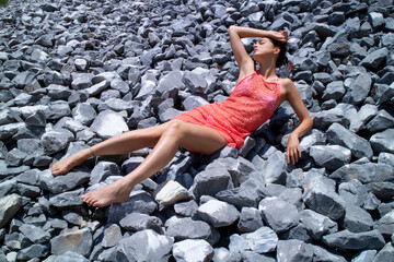 Beautiful brunette girl lying on an expanse of gray stones