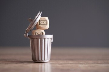 Closeup image of wooden cube with mail icon inside trash can. Junk mail and spam mail concept. - obrazy, fototapety, plakaty