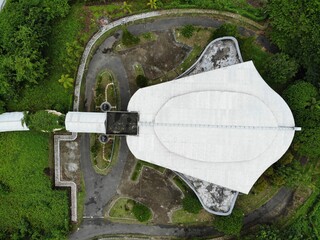 A top down aerial view of building shaped like a manta ray called Gedung Pari, surrounded by green trees in Waisai, Raja Ampat, West Papua, Indonesia. 