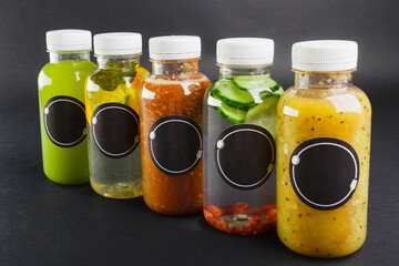 5 different bottles with detox drinks standing in a row. Bottles are labeled with black circle stickers.