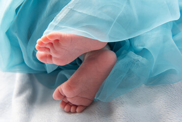 dolcissimo neonato che dorme su una morbida copertina azzurra,  dettaglio di piedini