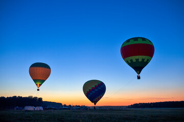 Scenic Line of Three Colorful Air Balloons Levitating Over the Field Outdoors Against Clear Blue Skies