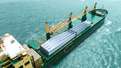 Wind Turbine on Ship, Transportation of blades for wind turbines on a cargo ship. Heavy load carrier on cargo ship loaded with Electric Wind Turbine Blades.