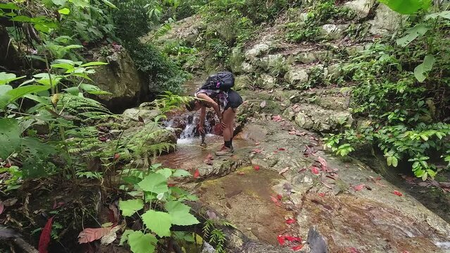 Woman on jungle hike uses phone to film low angle closeup waterfall