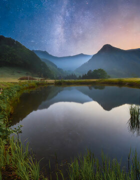 星空の下、穏やかな湖の夜明け