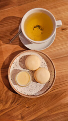 Breakfast, green tea in a large white mug, cheesecakes, close-up on a wooden table