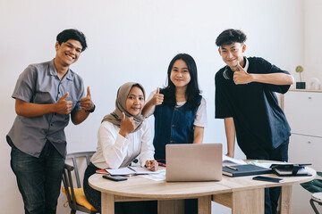 Group of Asian students show thumbs up while doing college project