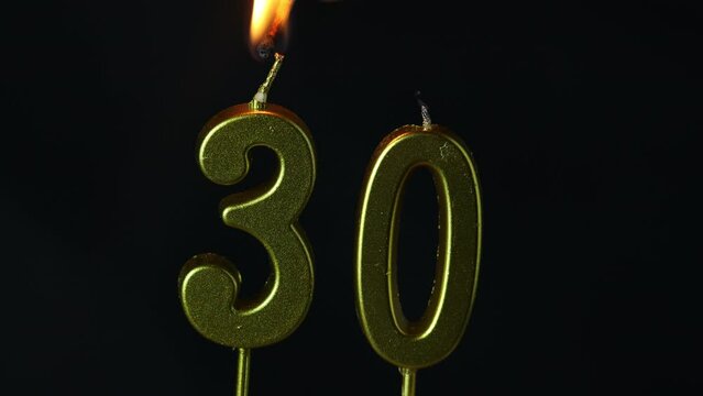 close up on the gold number thirty candle on a dark background.
 - Powered by Adobe