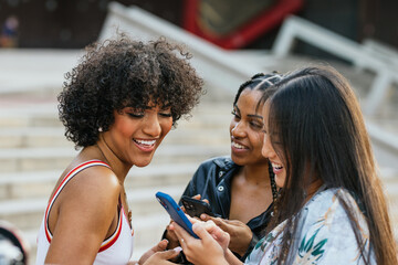 Multi-ethnic and multi-gender friends using phone in the street
