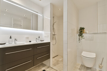 Fototapeta na wymiar a modern bathroom with white and brown cabinets, toiletries, sink, mirror and shower stall in the corner
