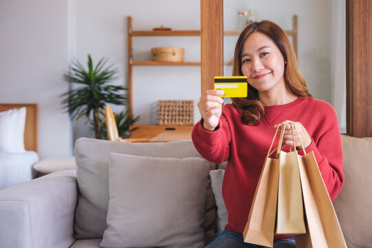 Portrait image of a woman with shopping bags holding and showing a credit card for purchasing