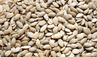 Background with raw hulled pumpkin seeds close-up