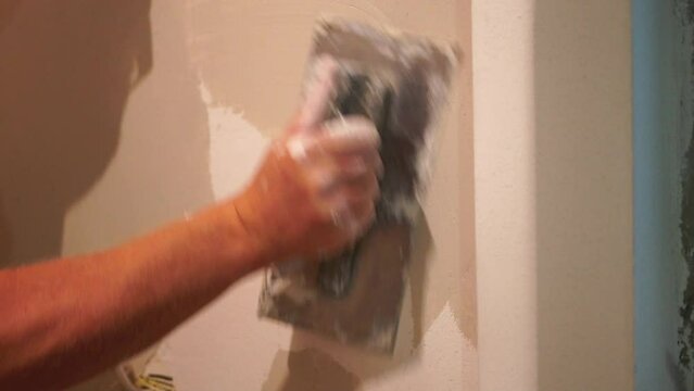 Male builder use metal spatula for putty walls, repairman filling spatula with spackling paste and covering cement wall surface. Builder leveling wall and angle Renovation work in Residential Premises