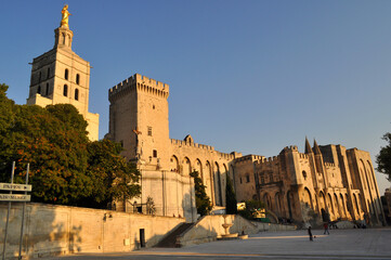 Fototapeta premium Avignon, France - Monumental building of the papal palace with the square illuminated by the setting sun.