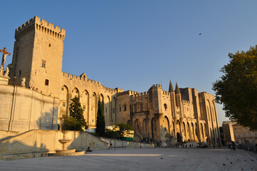 Fototapeta premium Avignon, France - Monumental building of the papal palace with the square illuminated by the setting sun.