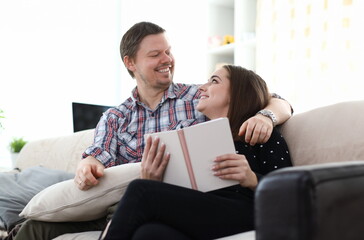 Happy couple reading book on sofa. Together education concept