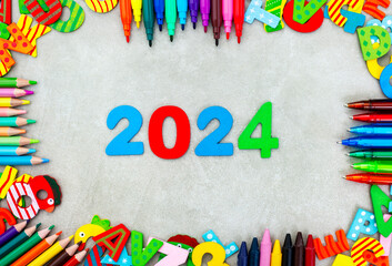 Colorful stationery and lettering in a frame on mottled grey with 2024 in bright numbers. New school year