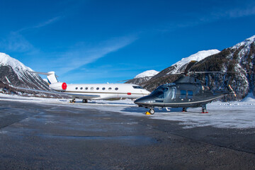 Luxury business jet and helicopter parked at the ramp in the engadin valley in the Swiss alps. The...