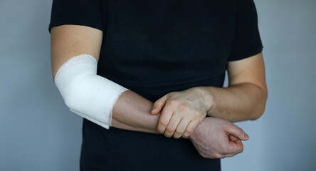 Male hand with tight elastic bandage on elbow closeup. Self help sprain concept