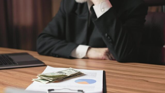 Cropped view of angry business person in suit throwing cash on clipboard with documents at executive desk. Aged general manager getting irritated about financial failure of corporate strategy team.