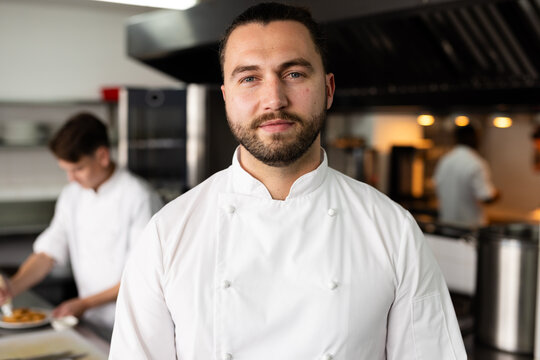Portrait of handsome caucasian male chef standing confidently in commercial kitchen